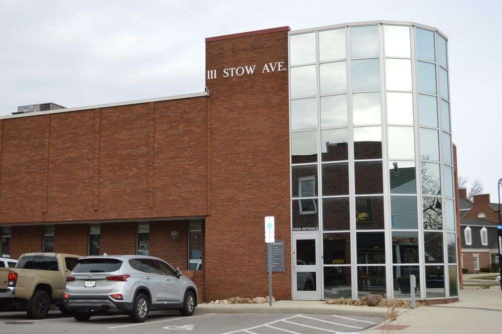 Modern brick building at 111 Stow Avenue with curved glass entrance and parking lot.