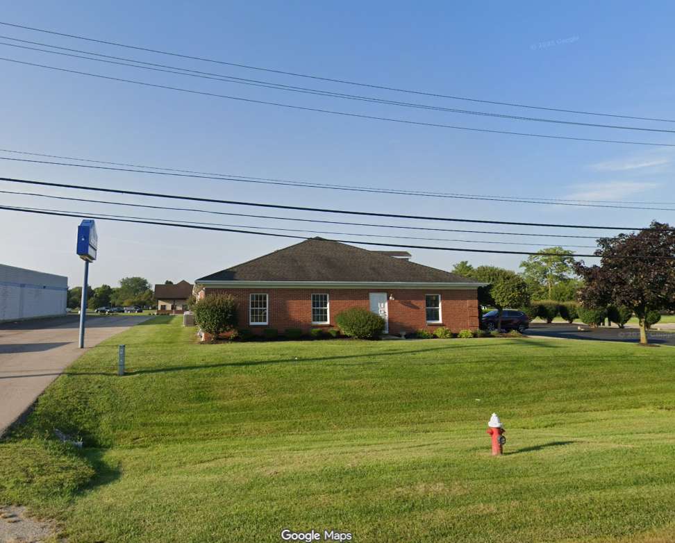 Single-story brick house with hip roof on landscaped lot along residential street.