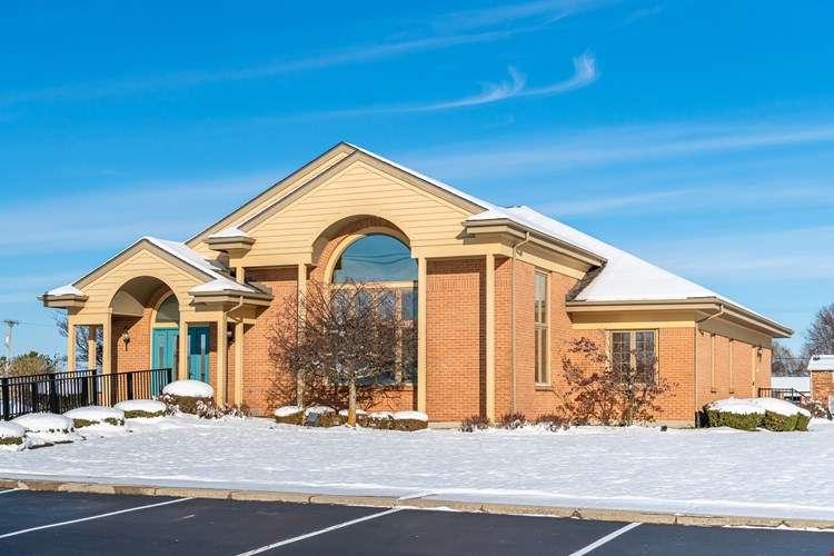 Modern brick residential home with curved architectural details and snow-covered grounds in winter.