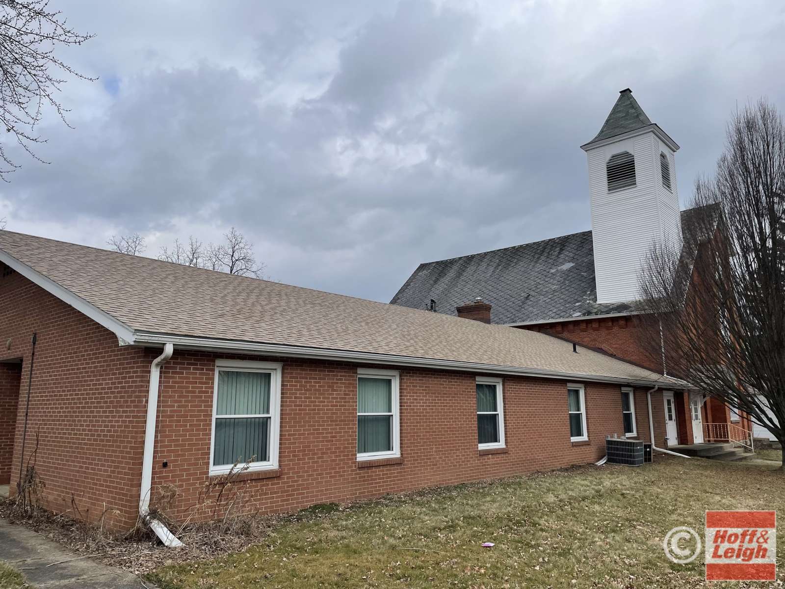 Brick church building with steeple at 3 E Church Street on an overcast day.