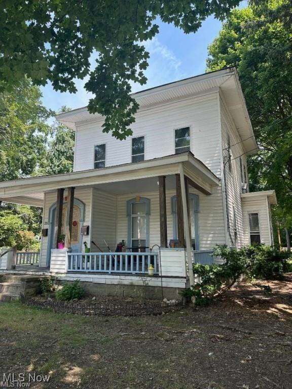 White two-story Victorian house with front porch surrounded by green trees at 39 Nelson Street, Painesville, OH.
