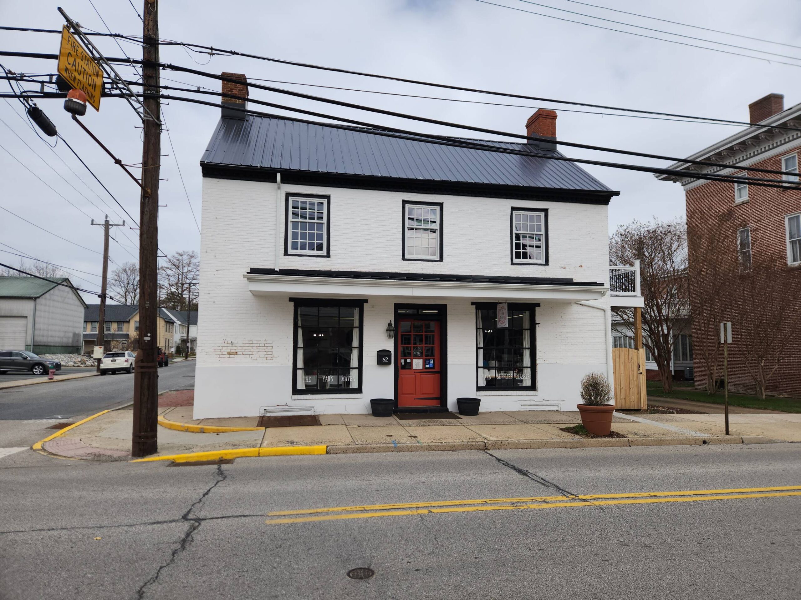 White two-story commercial building with red door and storefront windows on a small town street.