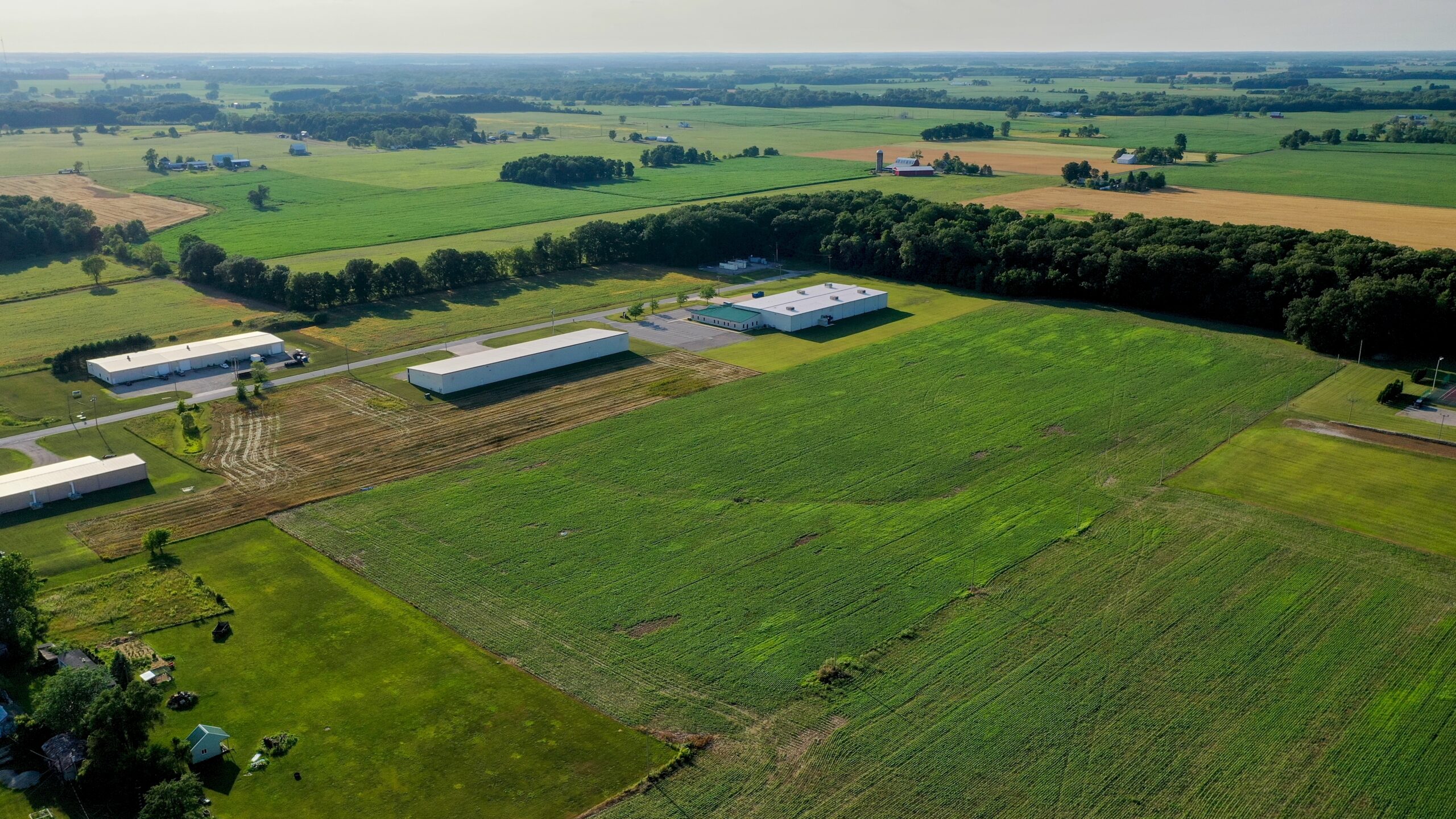 Aerial view of industrial greenhouses and agricultural fields in a rural landscape.
