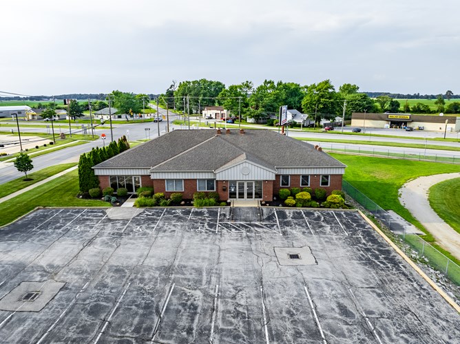 Aerial view of a brick commercial building with parking lot in a rural Ohio area surrounded by green fields.