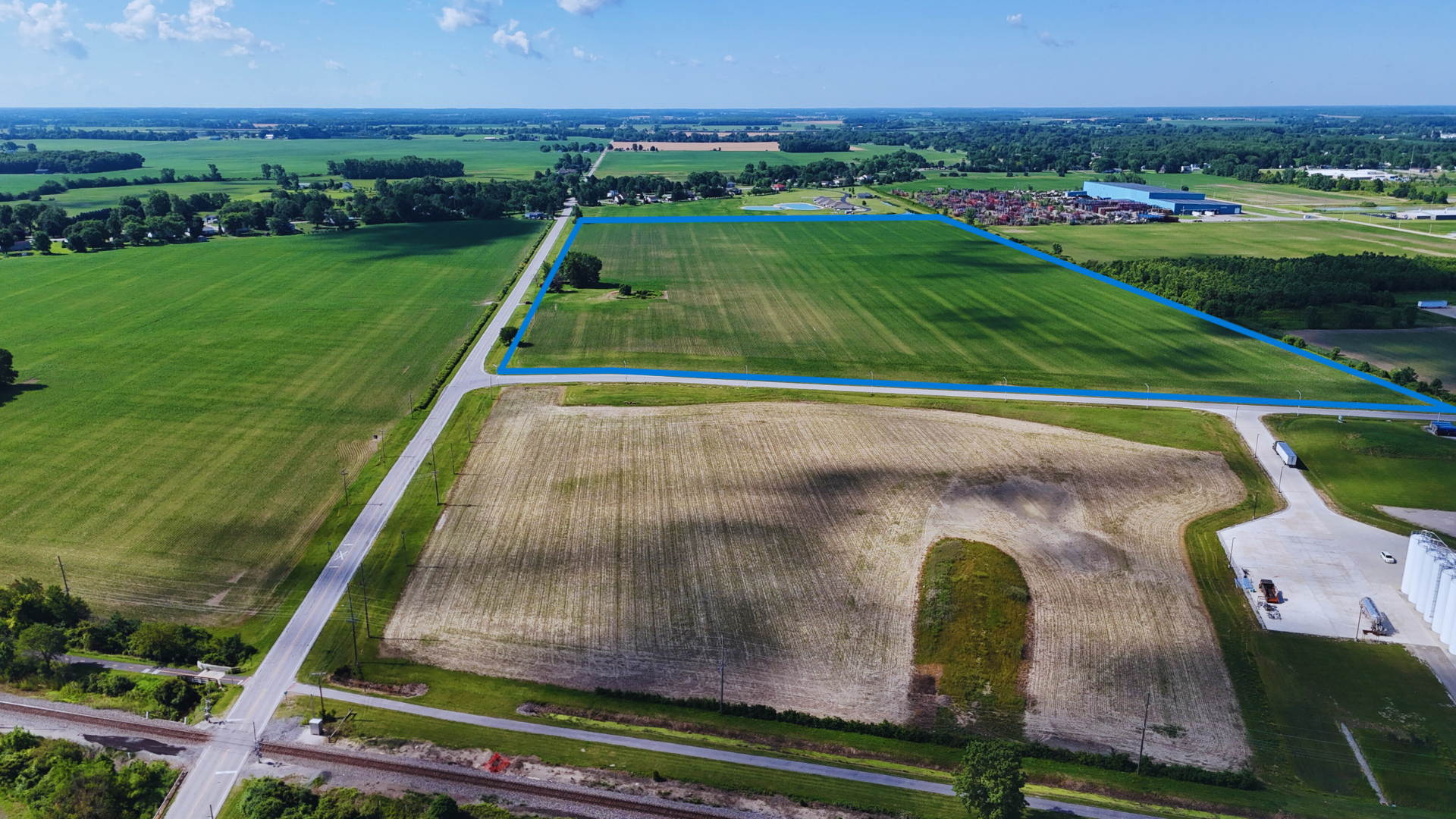 Aerial view of rural Dutch farmland with green fields, a plowed field, waterways, and scattered farm buildings.