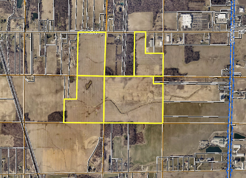 Aerial view of agricultural land parcels outlined in yellow, showing fields and rural development patterns.