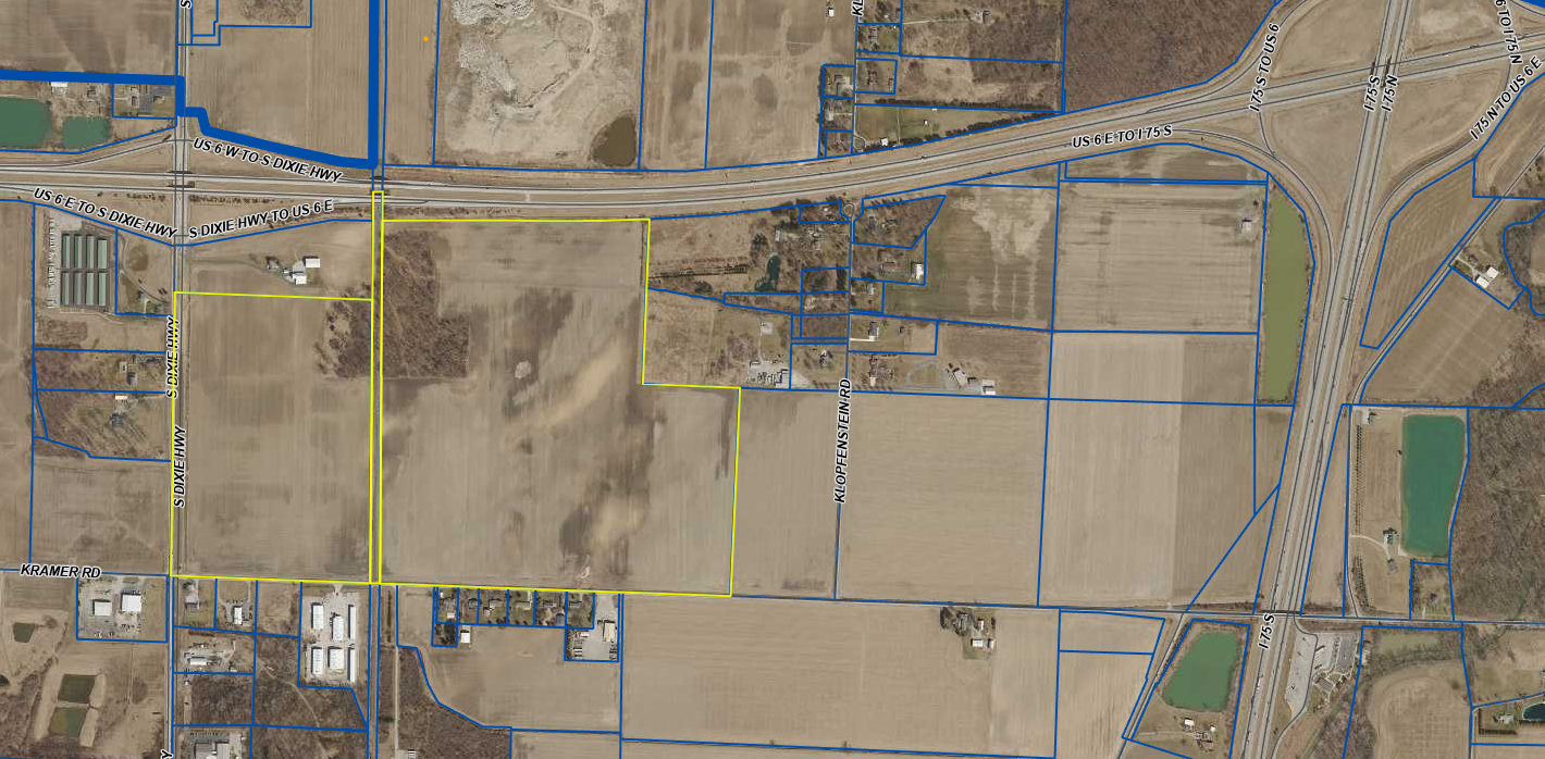 Aerial view of agricultural land with highway interchange and industrial facilities in a rural area.