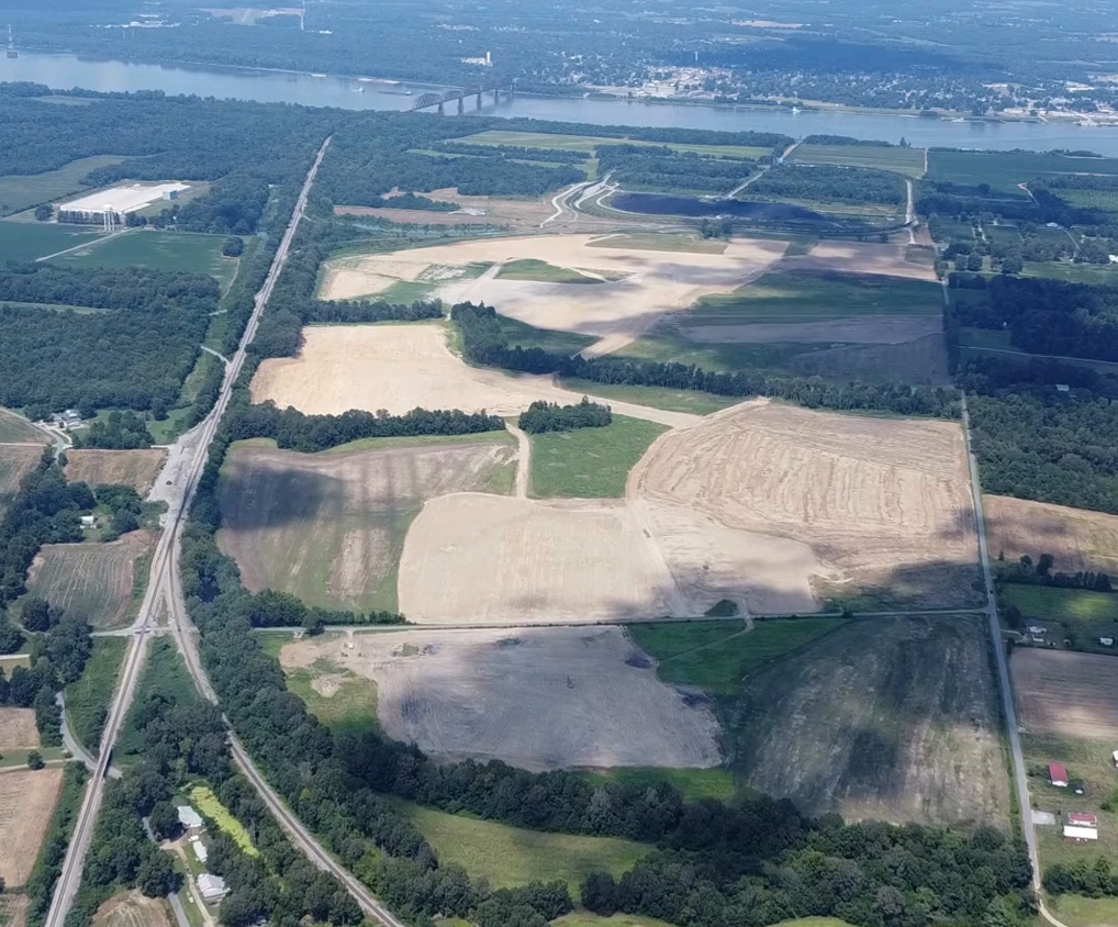 Aerial view of agricultural farmland with roads, forests, and waterways in a rural landscape.