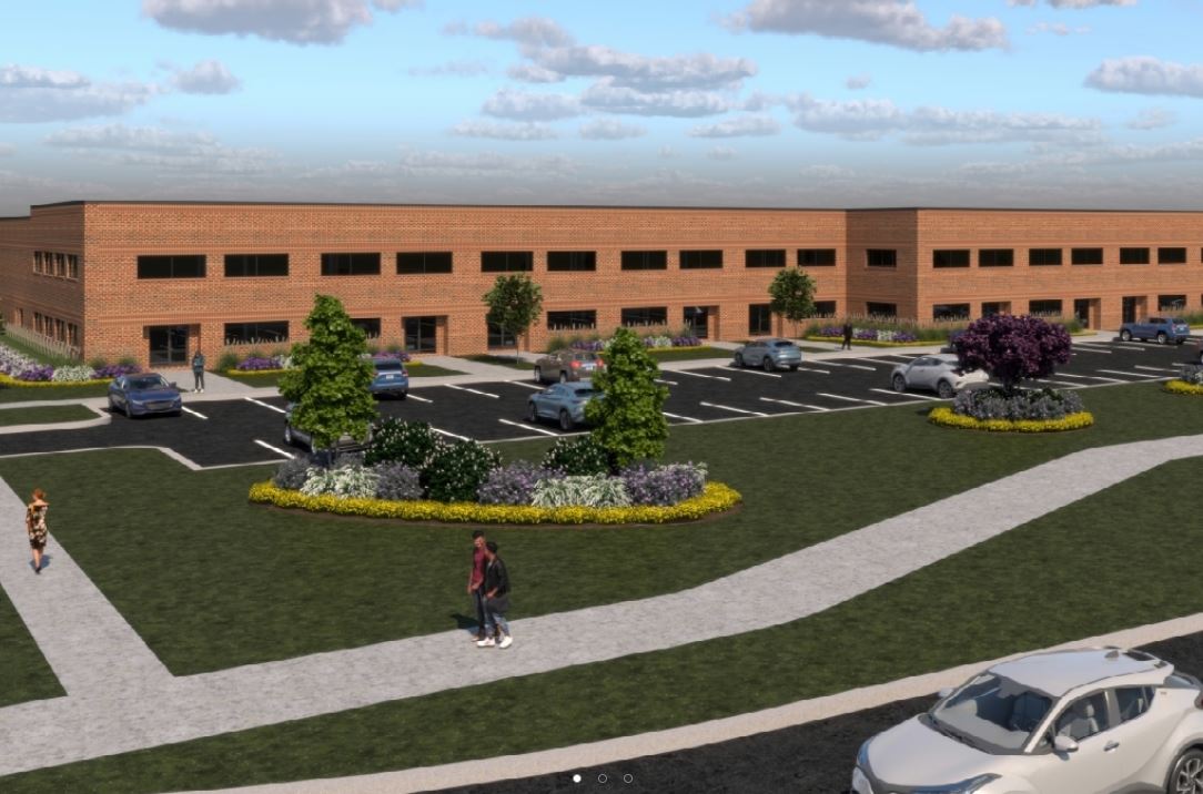 Rendering of a modern brick building with a spacious parking lot, landscaped grounds, and pedestrian walkways.