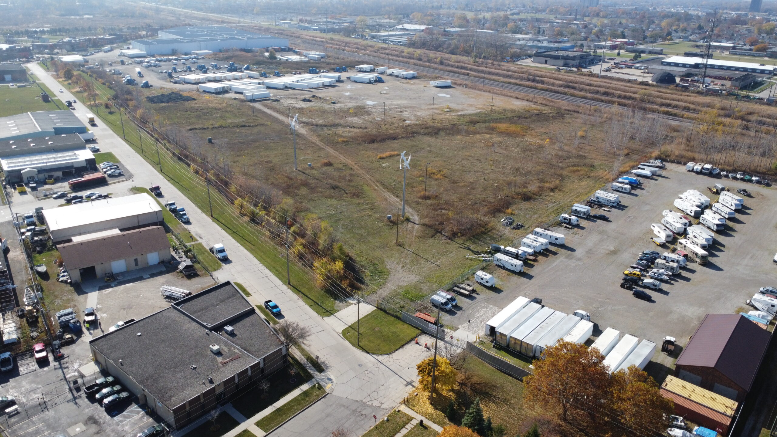 Aerial view of an industrial and commercial area with parking lots, warehouses, and open fields.