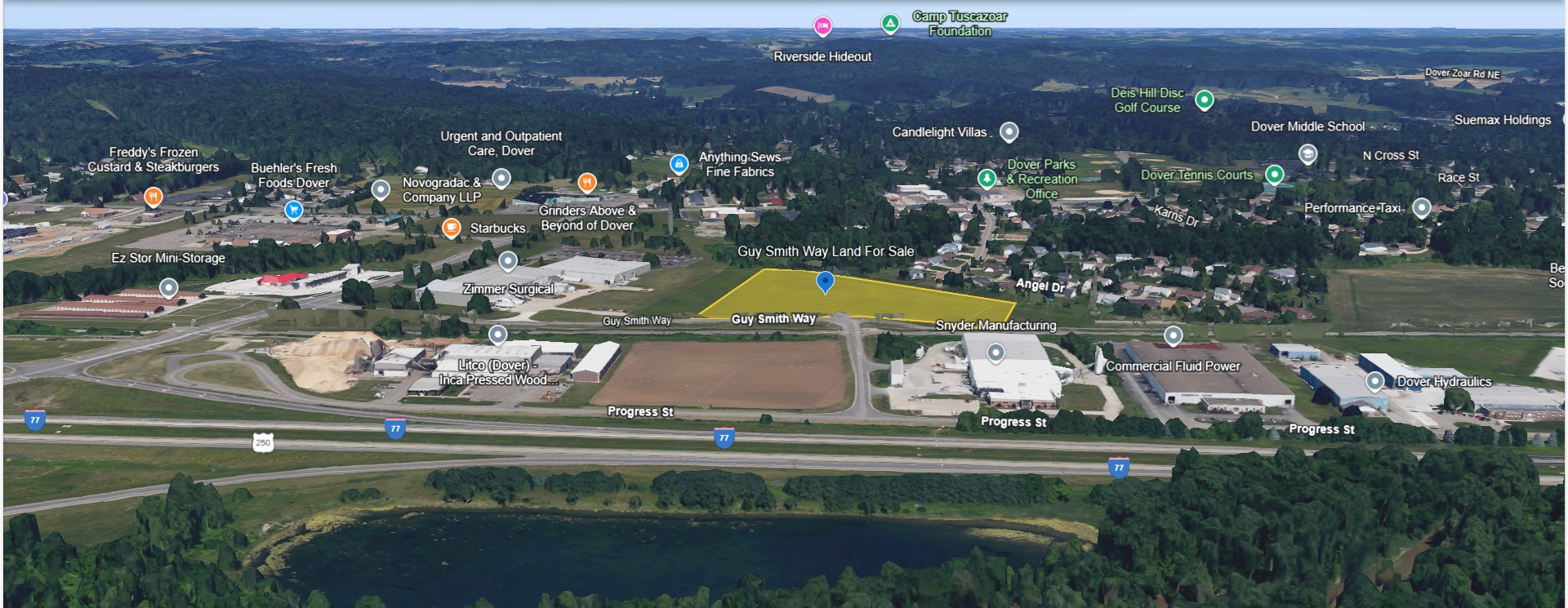 Aerial view of a highway corridor with industrial facilities, farmland, and forested areas alongside a river bend.