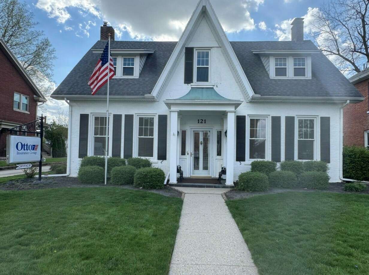 White colonial-style house with black shutters and an American flag at 121 N Wayne Street.