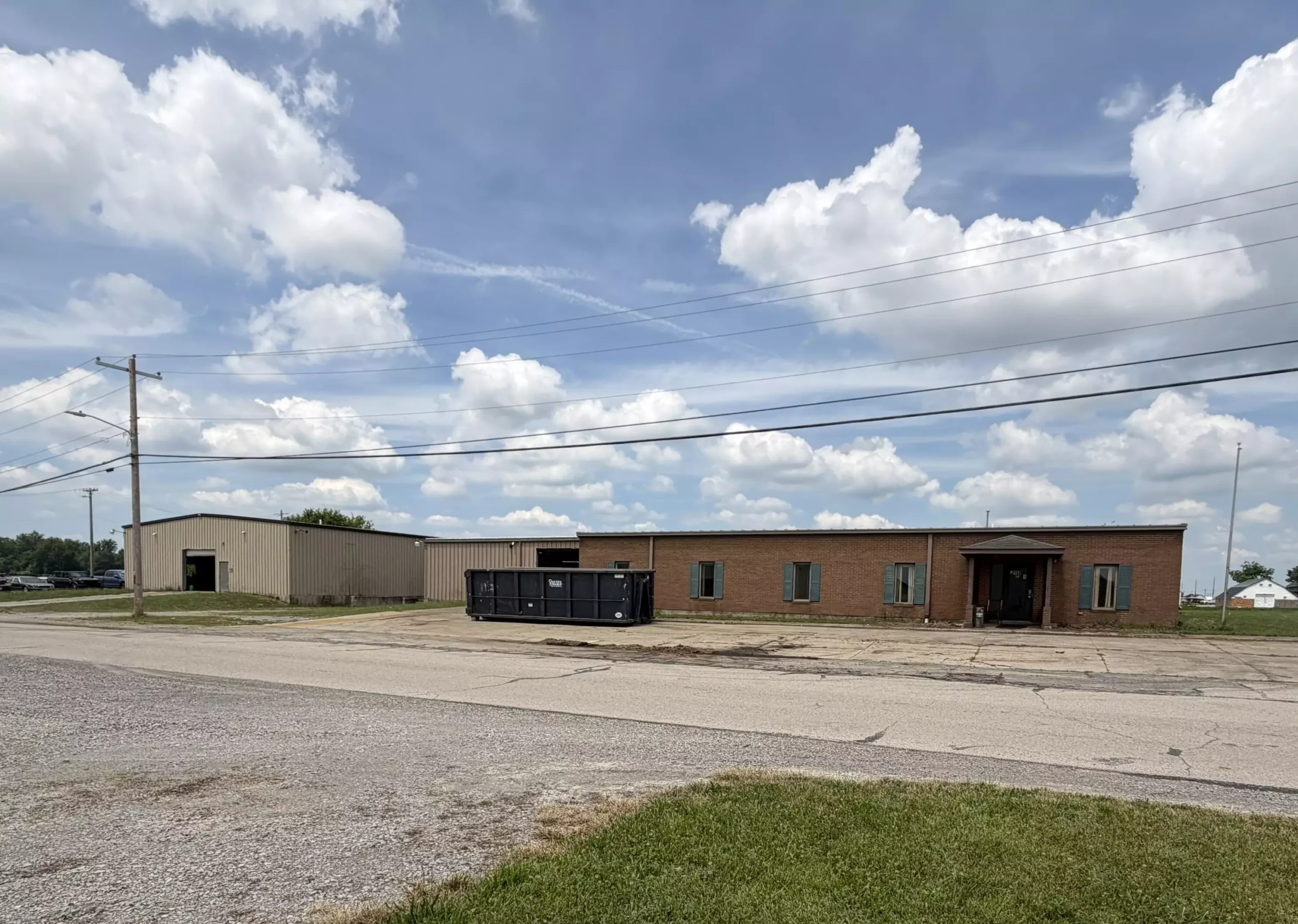 Industrial commercial building with metal and brick construction under blue sky with white clouds.