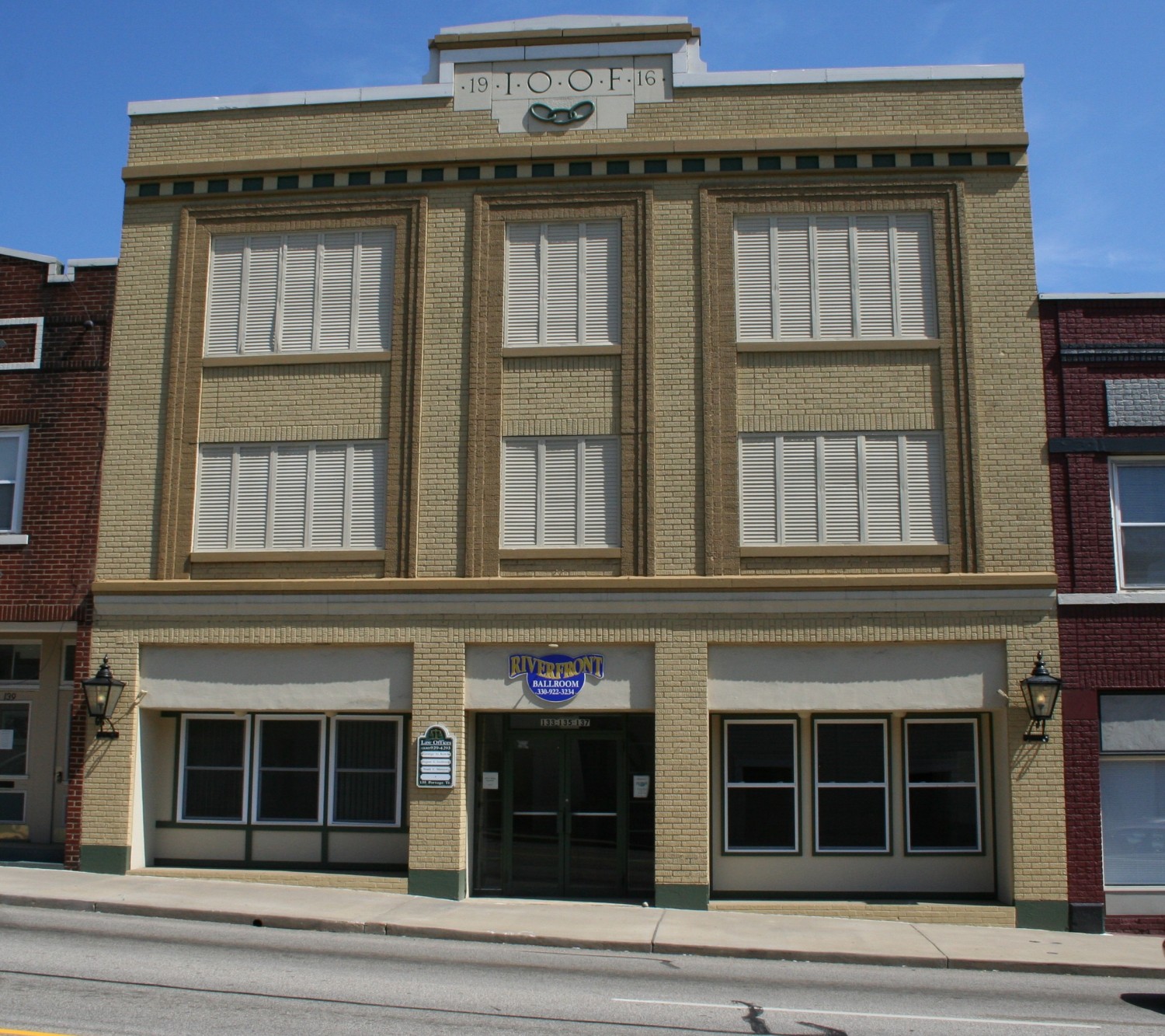 Historic brick building with yellow-tan facade, large windows, and "ROOF" text visible on roofline.